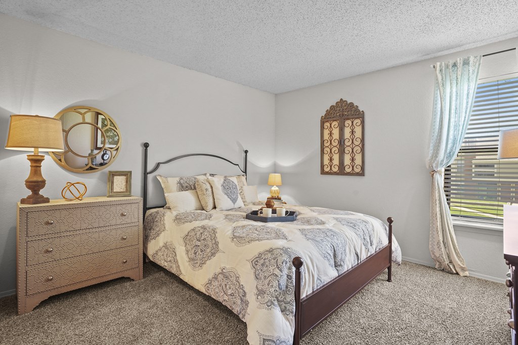 A bedroom with a bed, nightstand, and window.