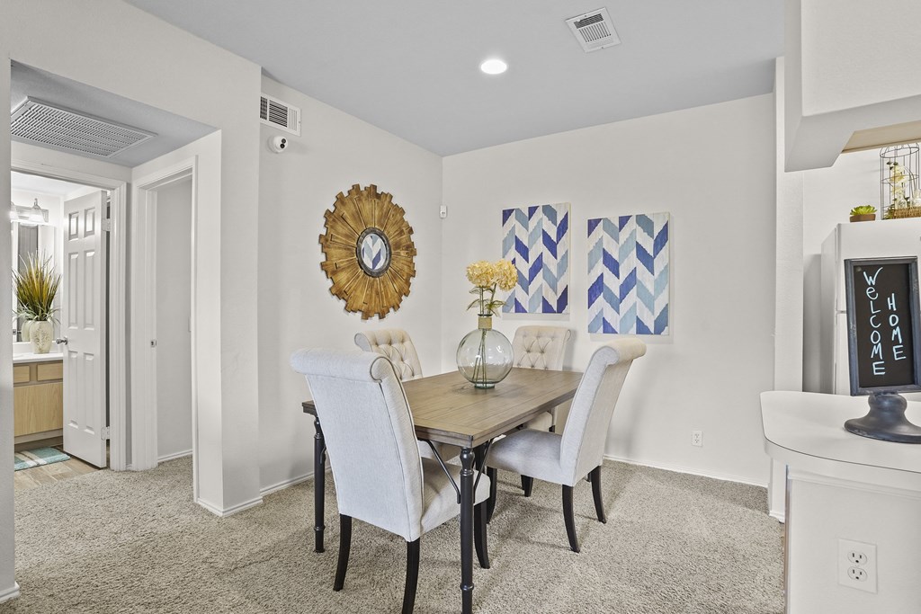 A dining room with a wooden table and white chairs.