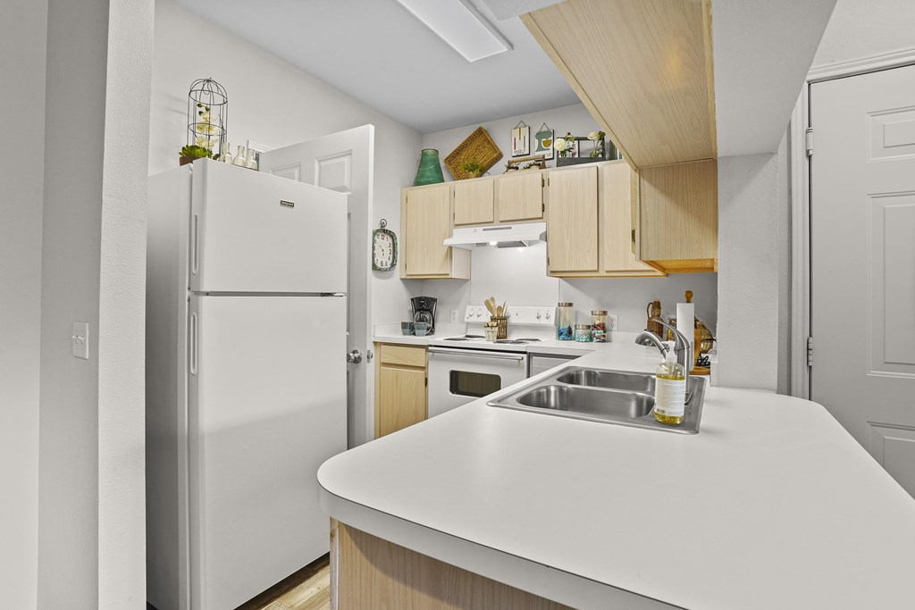 A kitchen with a white counter top and a white refrigerator.
