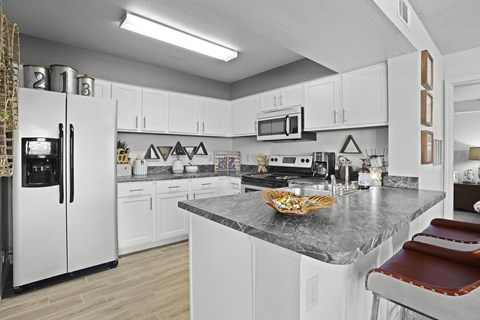A kitchen with white cabinets and a marble countertop.