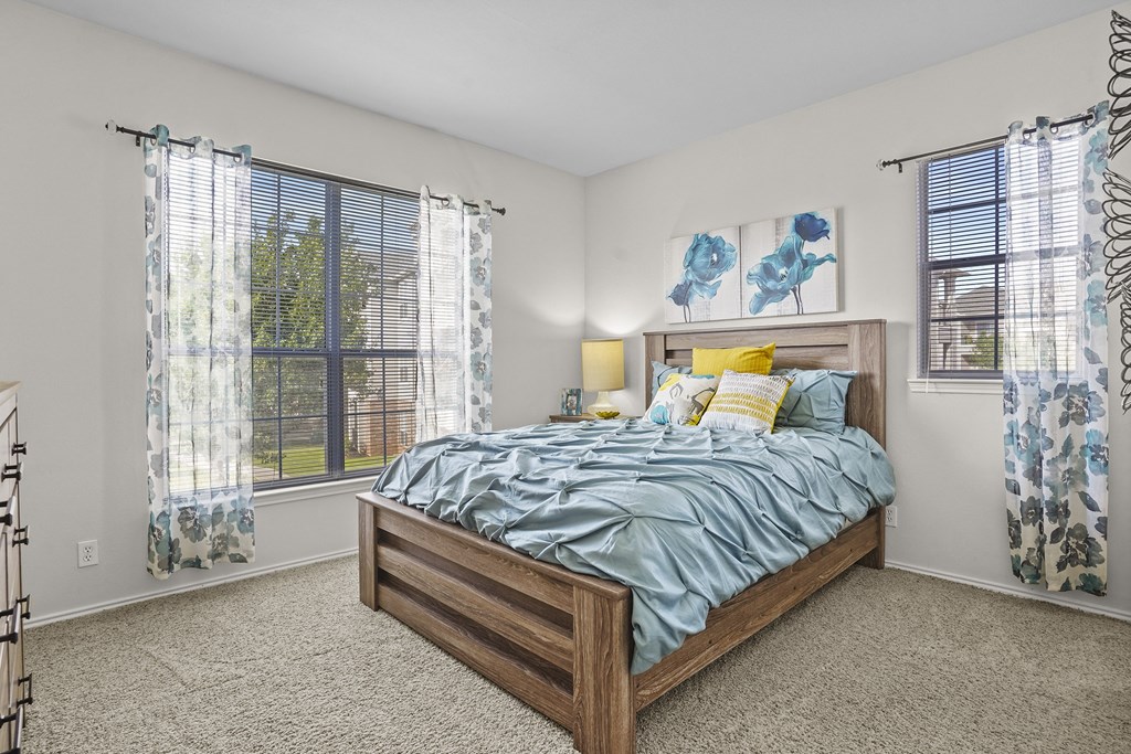A bedroom with a bed, two lamps, and a painting on the wall.