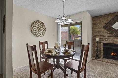A dining room with a table set for four and a fireplace.