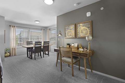 A dining room with a table set for two and a bicycle picture on the wall.