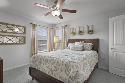 A bedroom with a large bed and a ceiling fan.