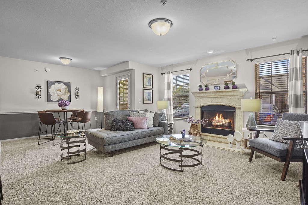 A living room with a fireplace and a grey couch.