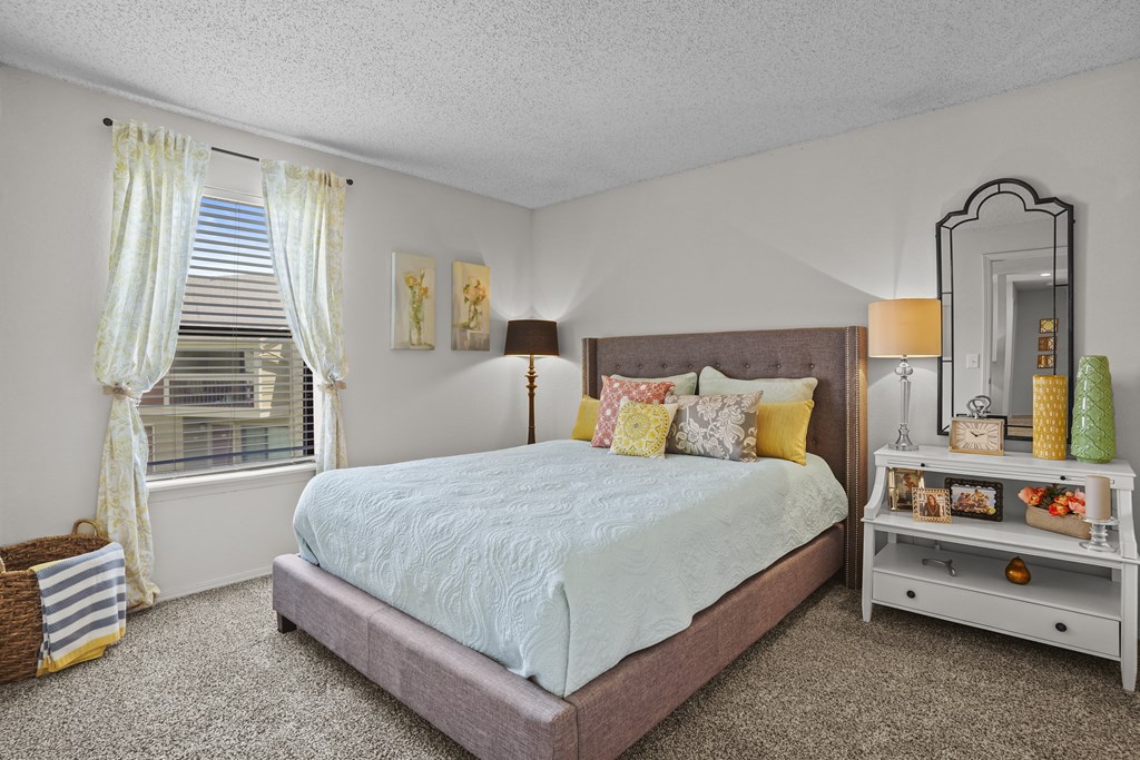 A bedroom with a bed, nightstand, and window.