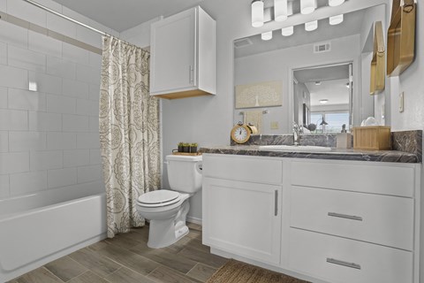 A white bathroom with a toilet, sink, and a mirror.