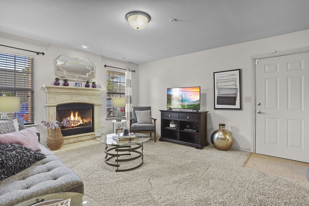 A living room with a fireplace, a grey sofa, a coffee table, and a TV.