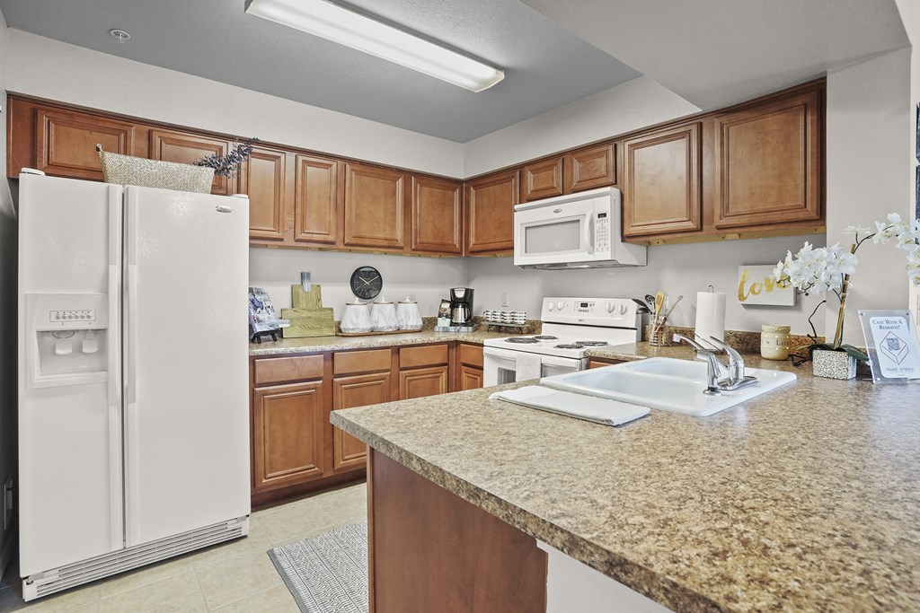 A kitchen with a white refrigerator and wooden cabinets.
