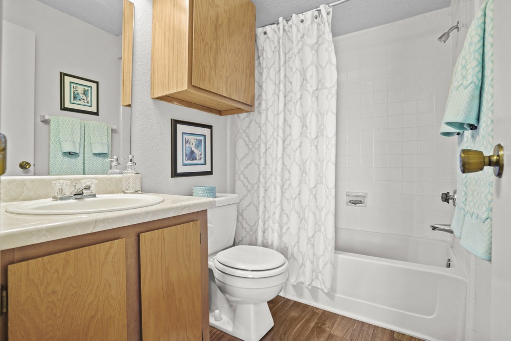 A white toilet sits in a bathroom with a white shower curtain.