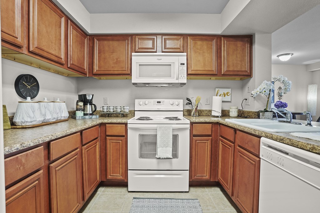 A kitchen with wooden cabinets and a white stove top oven.