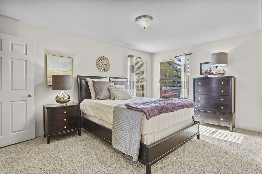 A bedroom with a bed, nightstand, and dresser.