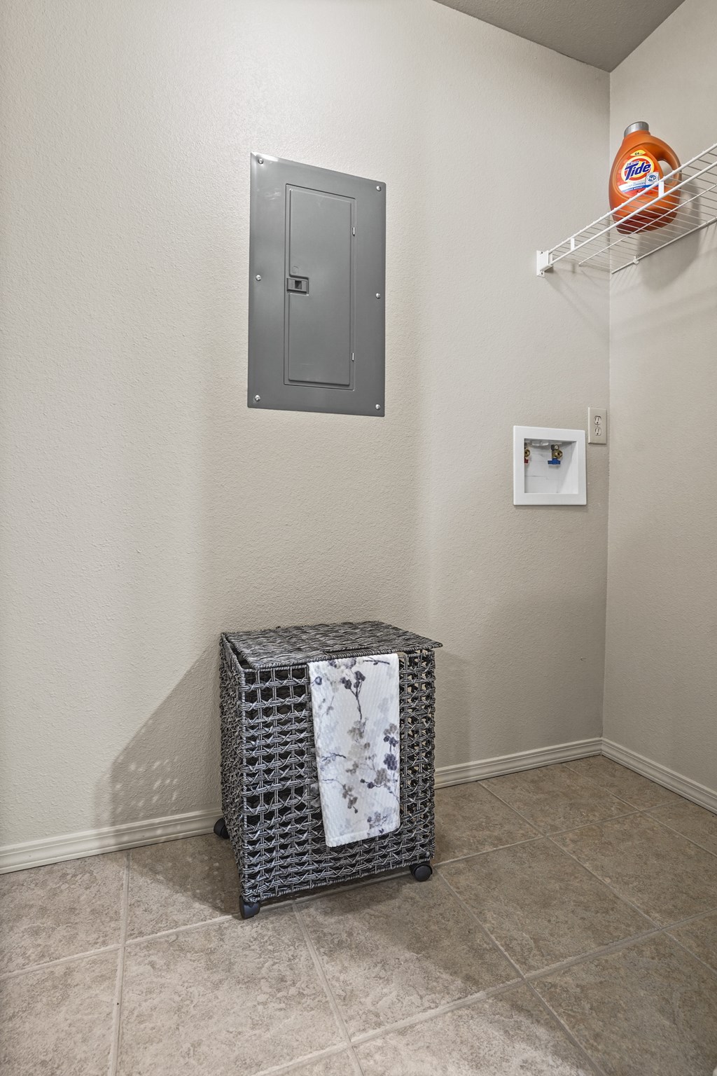 A small black and white basket sits on a tiled floor in a room.
