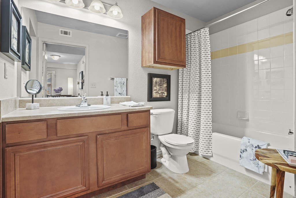 A bathroom with a white toilet and a wooden vanity.