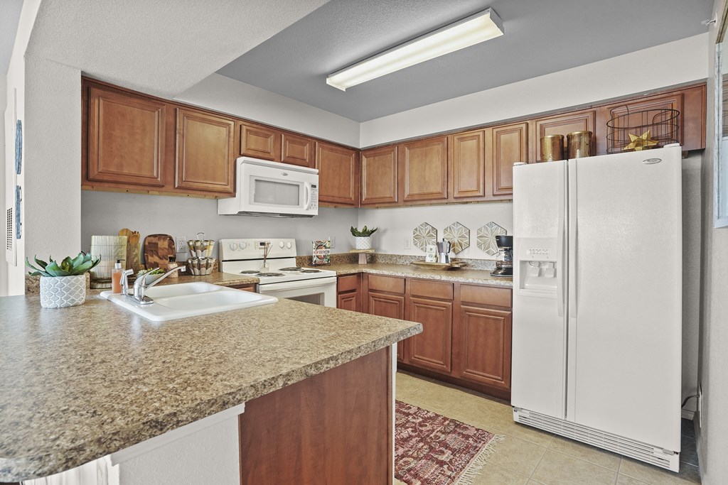A kitchen with a granite countertop and white appliances.