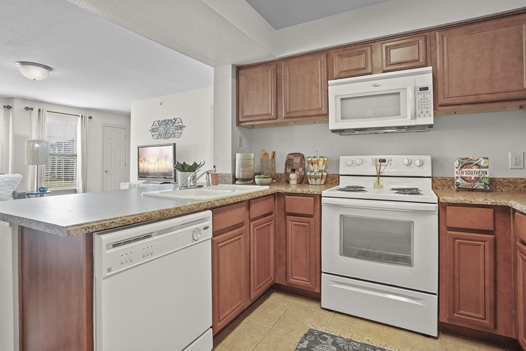 A kitchen with brown cabinets and white appliances.
