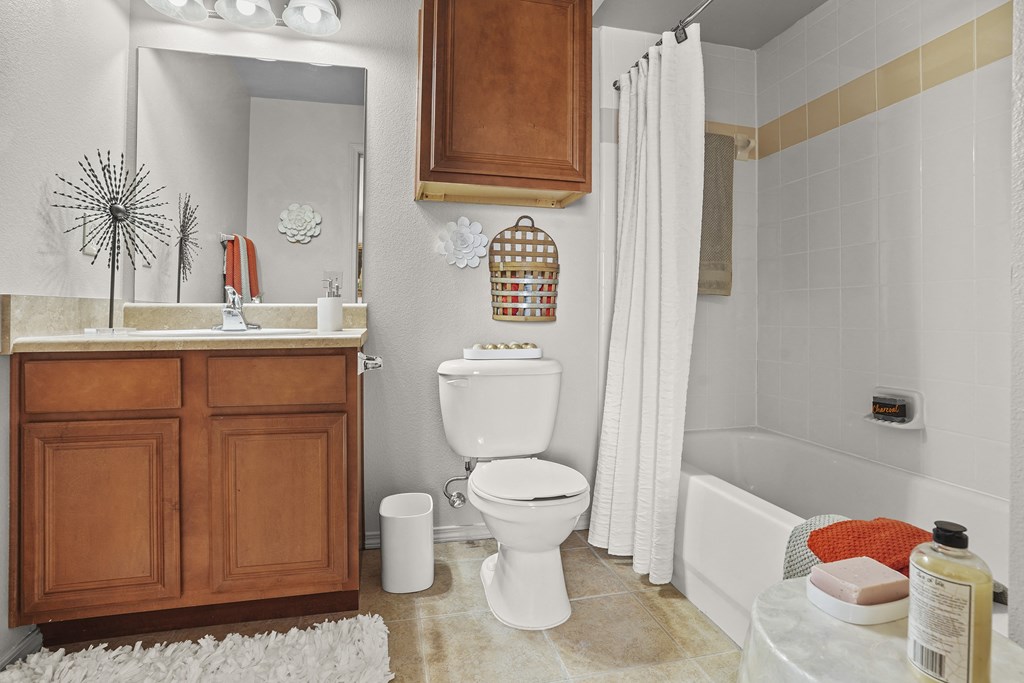 A white toilet sits in a bathroom next to a white sink and a white bathtub.