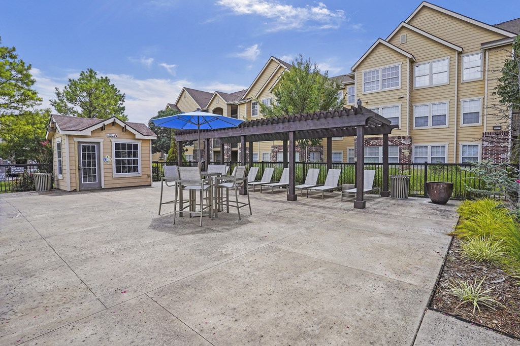 A patio area with a table and chairs under a pergola.