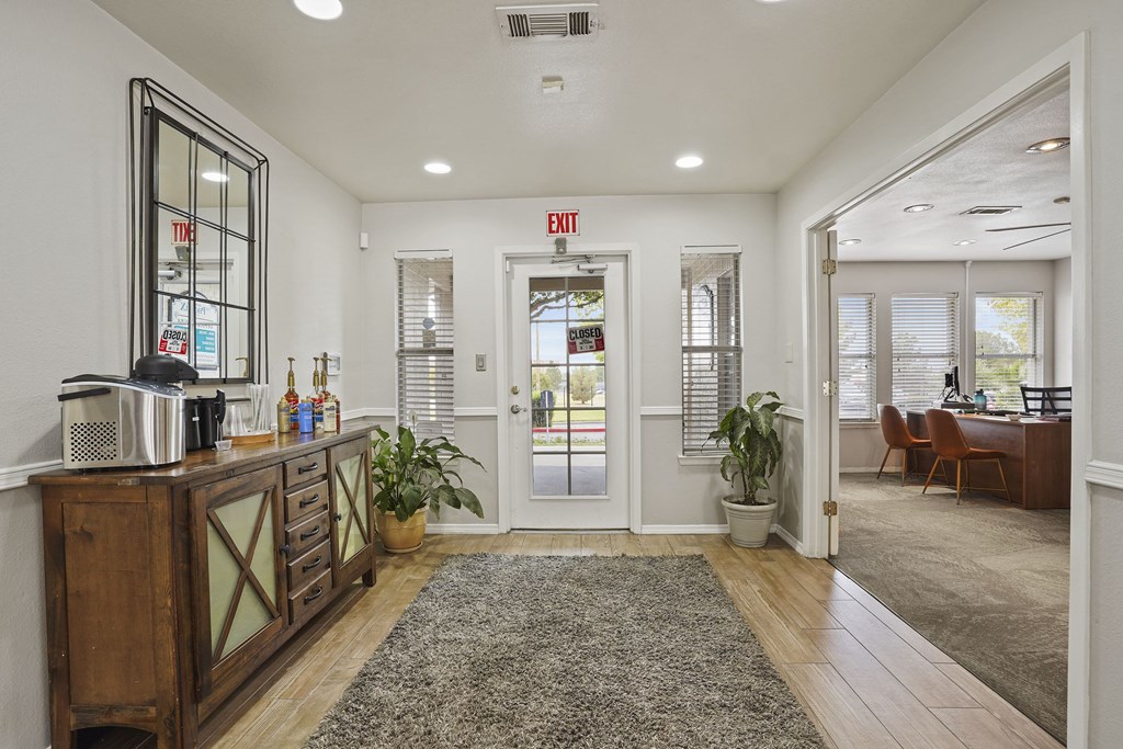 A reception area with a wooden desk and a rug on the floor.