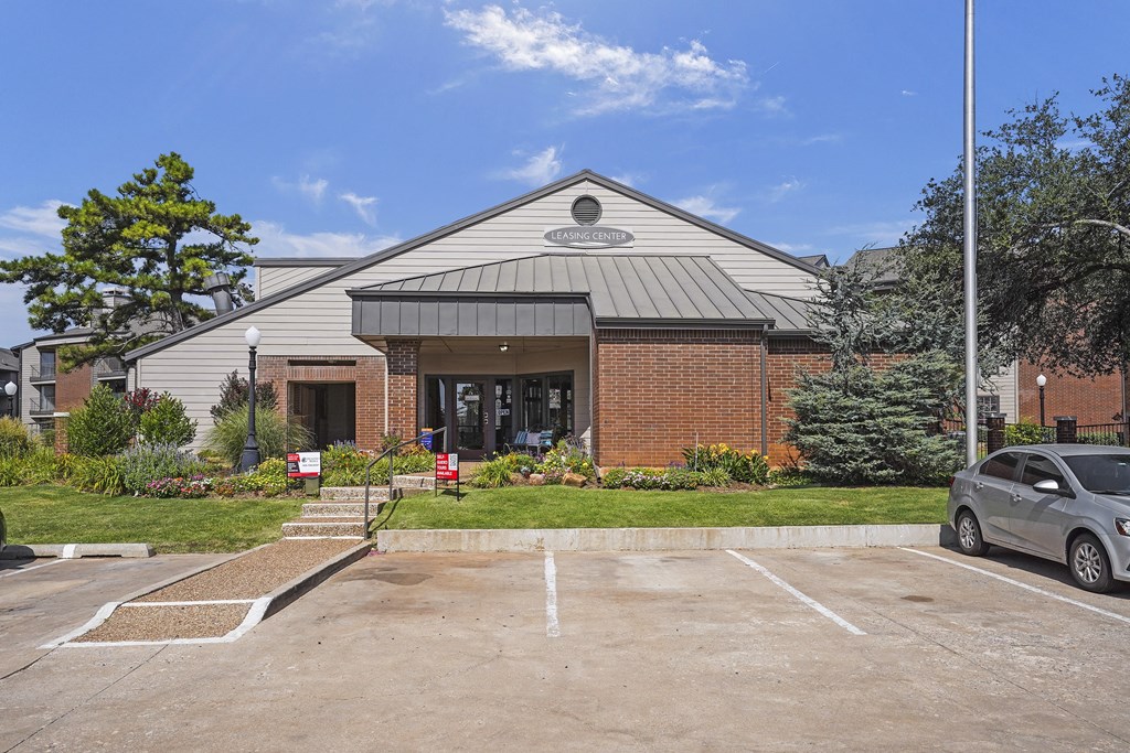 A grey car is parked in a parking lot in front of a building.