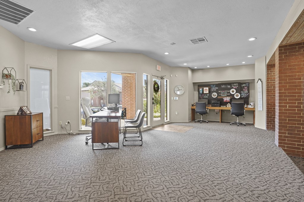 A spacious office room with a desk, chairs, and a bulletin board on the wall.