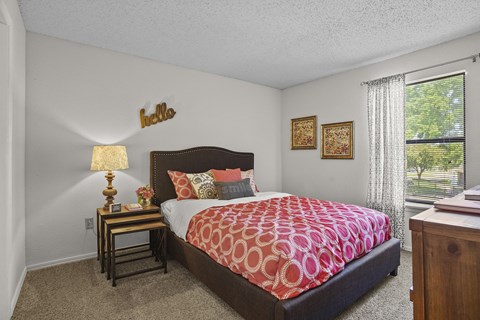 A bedroom with a large bed and a lamp on a side table.