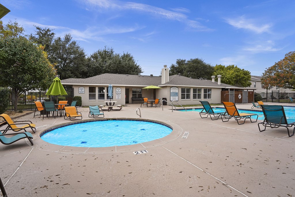 A pool area with chairs and a house in the background.