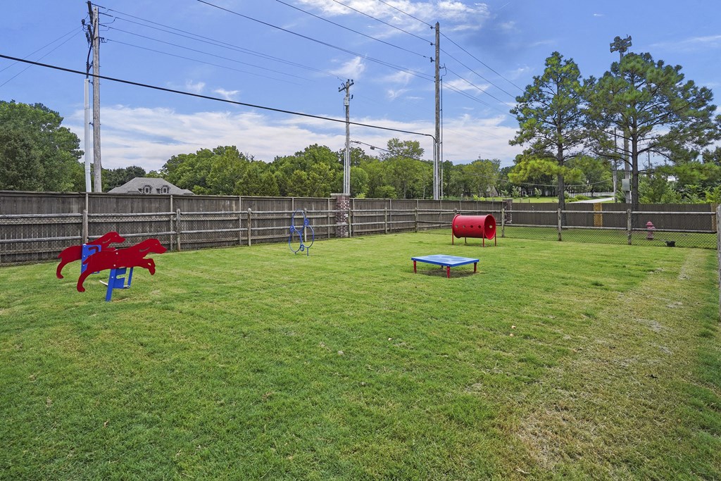 A backyard with a red sculpture, a blue bench, and a red barrel.