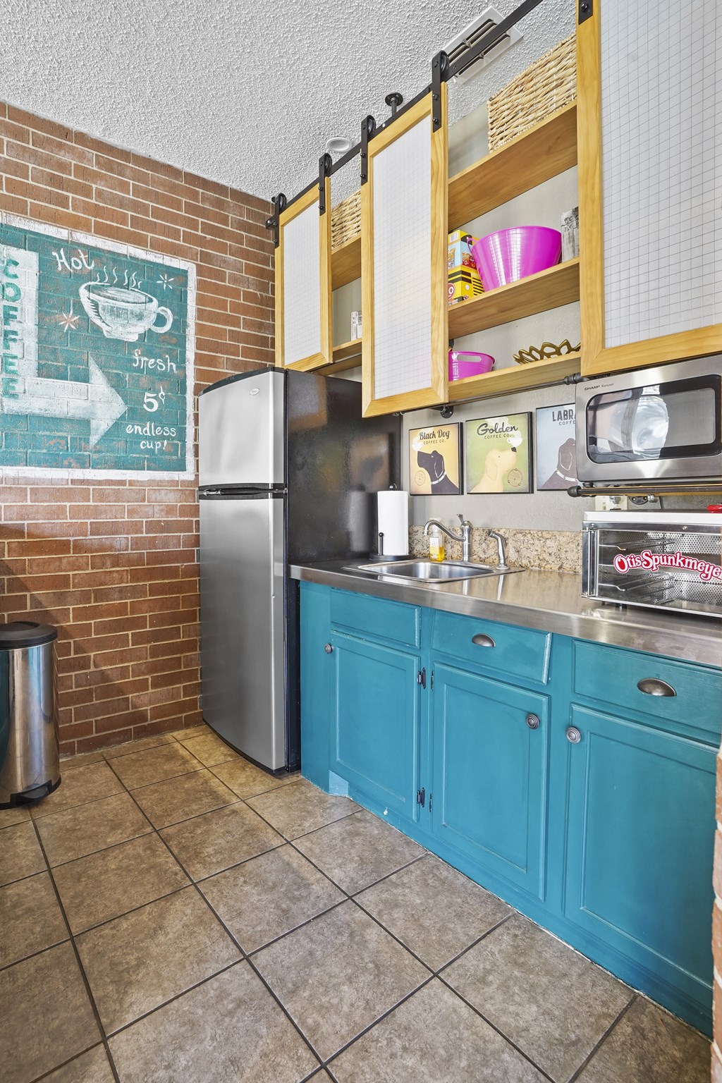 A kitchen with a refrigerator, sink, and cabinets.