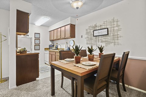 A dining room with a table set for two and a plant on the table.
