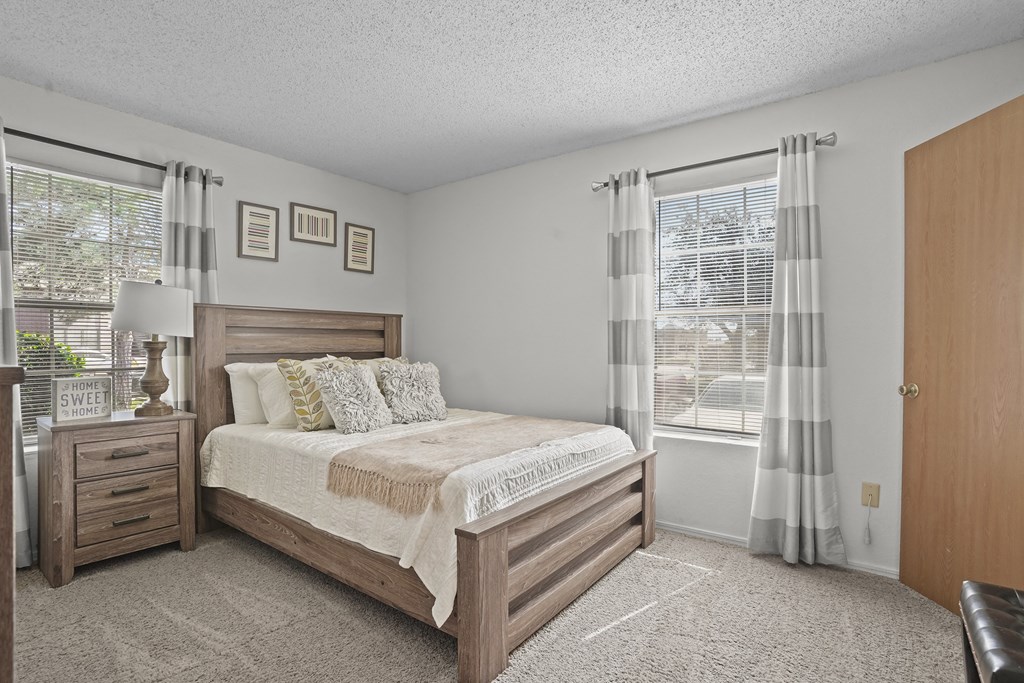 A bedroom with a bed, nightstand, and window.