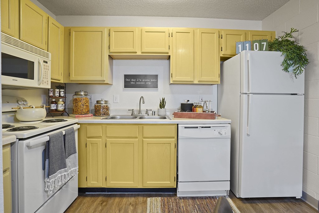 A kitchen with yellow cabinets and white appliances.