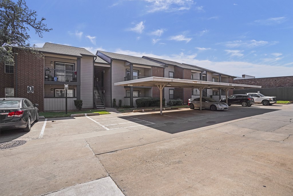 A parking lot in front of a building with cars parked.
