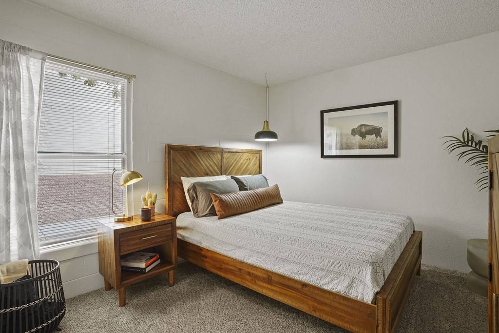 A bedroom with a large bed and a small nightstand with a lamp.