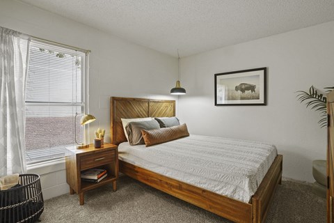 A bedroom with a large bed and a small nightstand with a lamp.