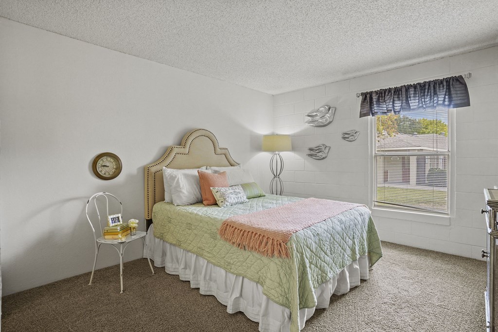 A bedroom with a bed, nightstand, and window.