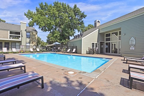 A pool area with a bench and a building in the background.