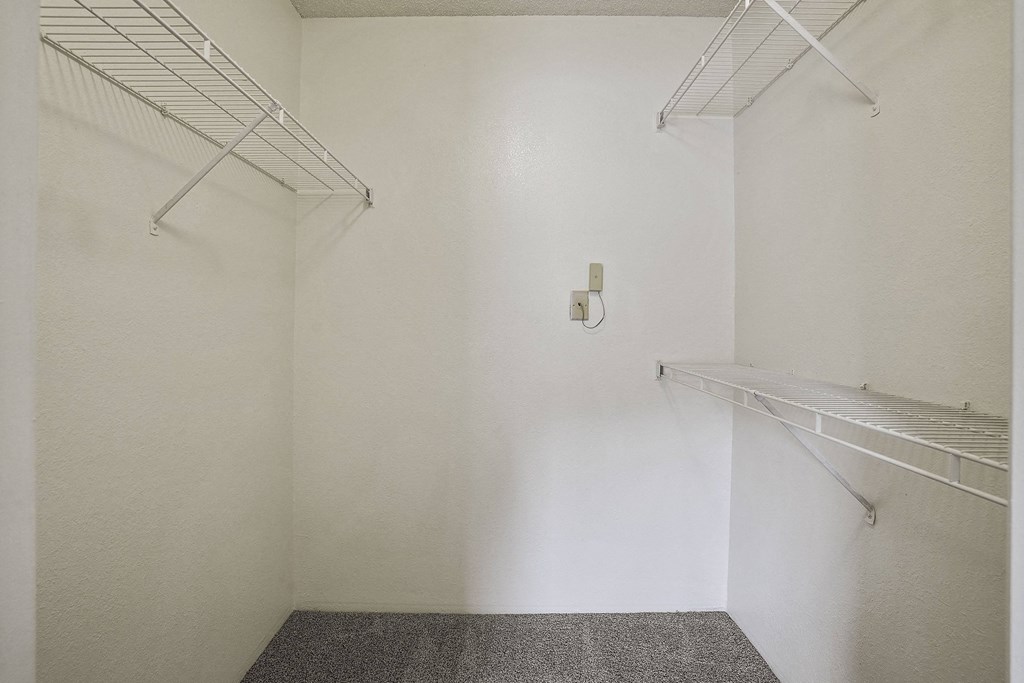 A white wall with a switch and two shelves.