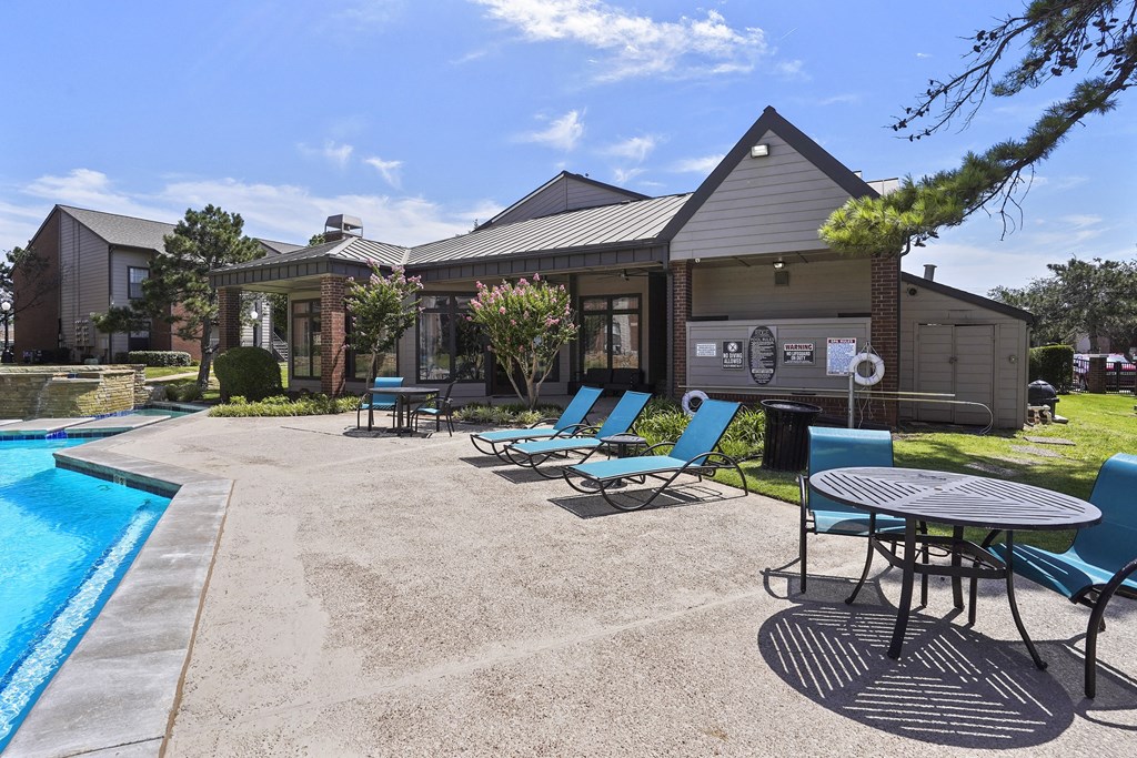 A poolside area with chairs and a table.