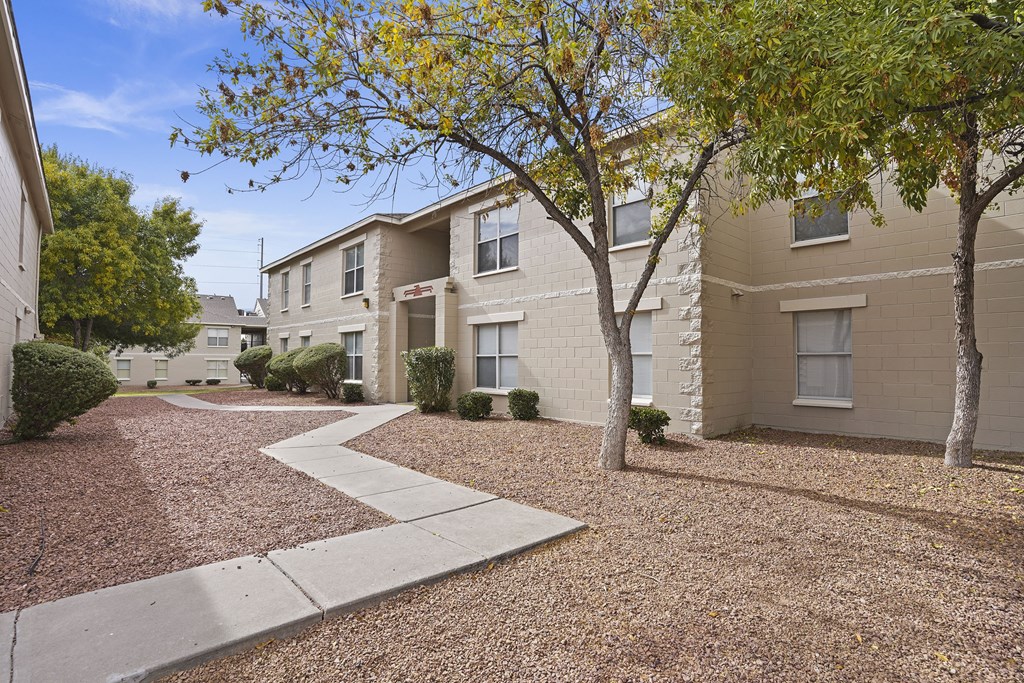 Apartment complex with a gravel driveway and trees.