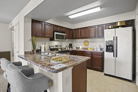 A kitchen with a marble countertop and a refrigerator.