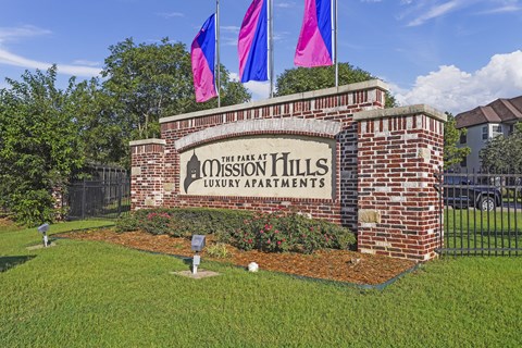 The sign for The Park at Mission Hills Luxury Apartments is displayed on a brick wall.