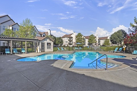A swimming pool surrounded by a fence and chairs.