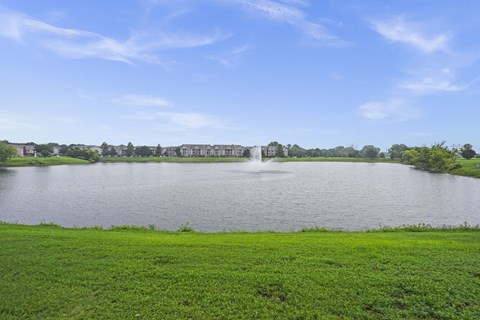 A large body of water with a fountain in the middle and buildings in the distance.