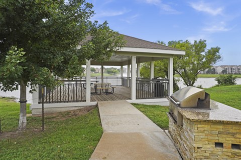 A gazebo is surrounded by a fence and a brick wall.