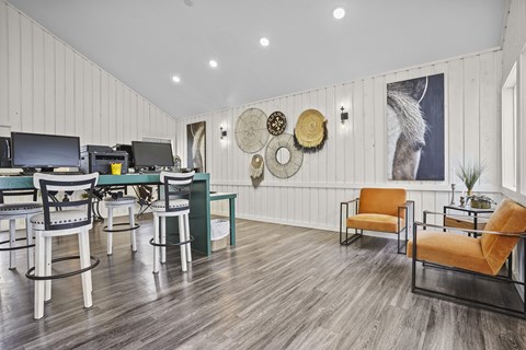 A room with a white wooden wall and a grey wooden floor with a dining table and chairs.
