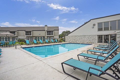A pool area with sun loungers and a building in the background.