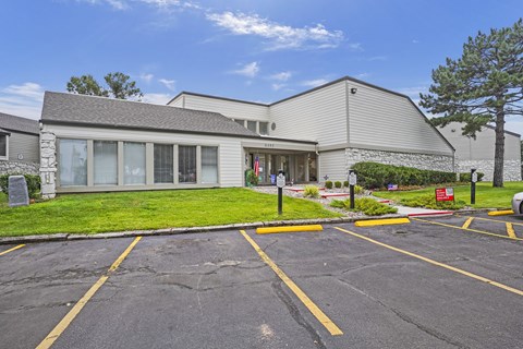 A parking lot in front of a building with a grey roof.