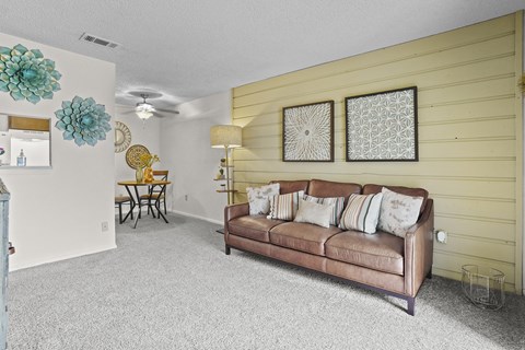 A living room with a brown couch and two decorative wall hangings.
