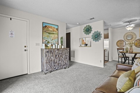 A living room with a brown leather couch and a grey carpet.